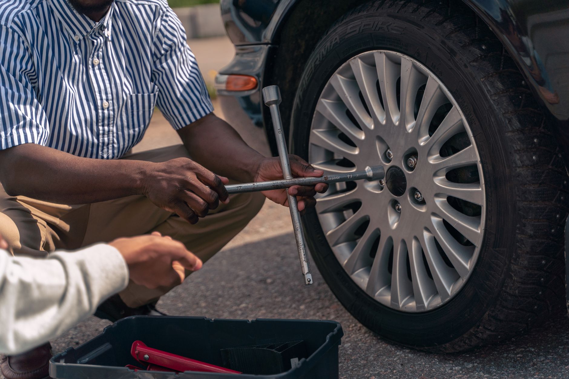 Person preparing to change a flat tire on a vehicle