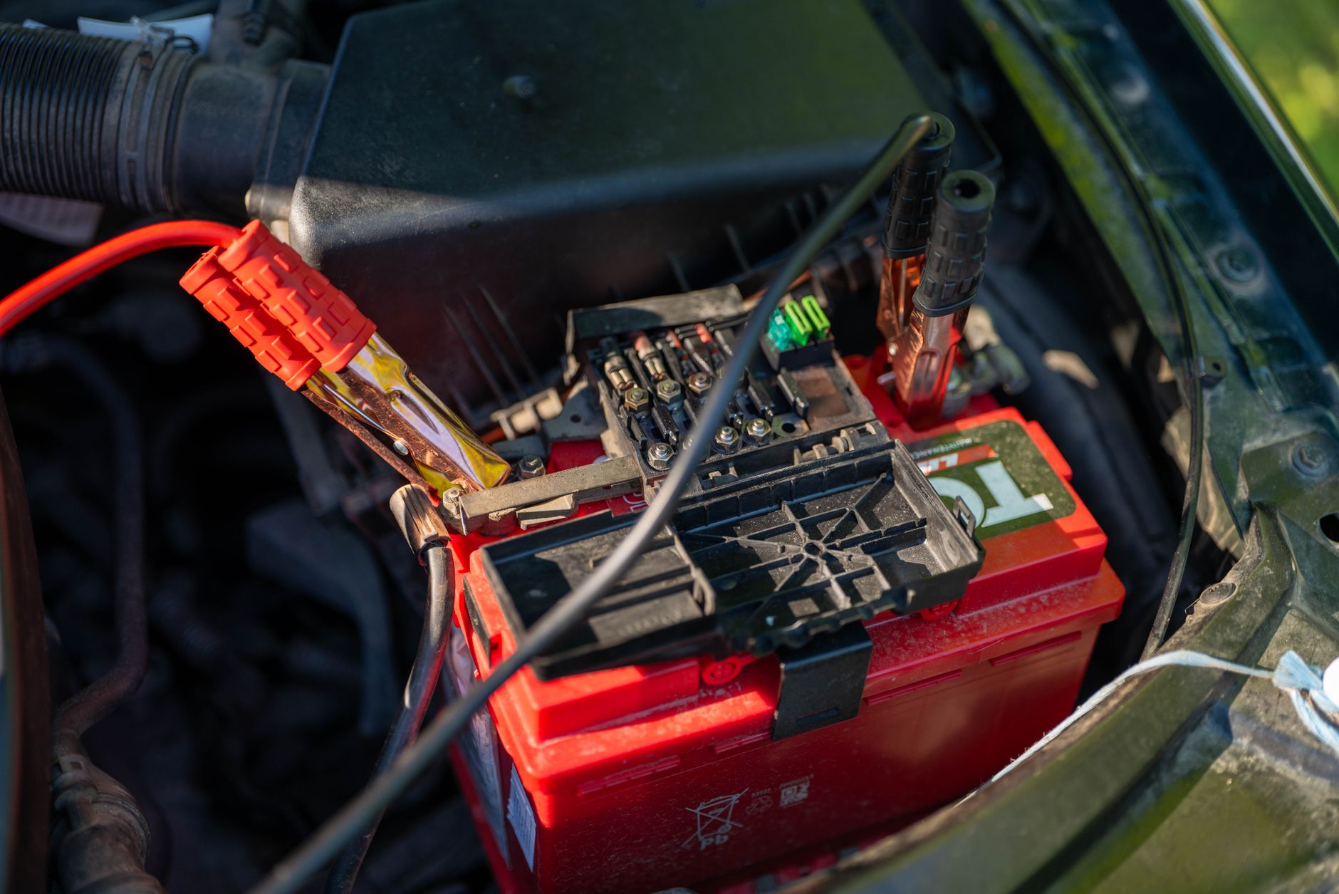 Close up of jumper cables connected to a car battery