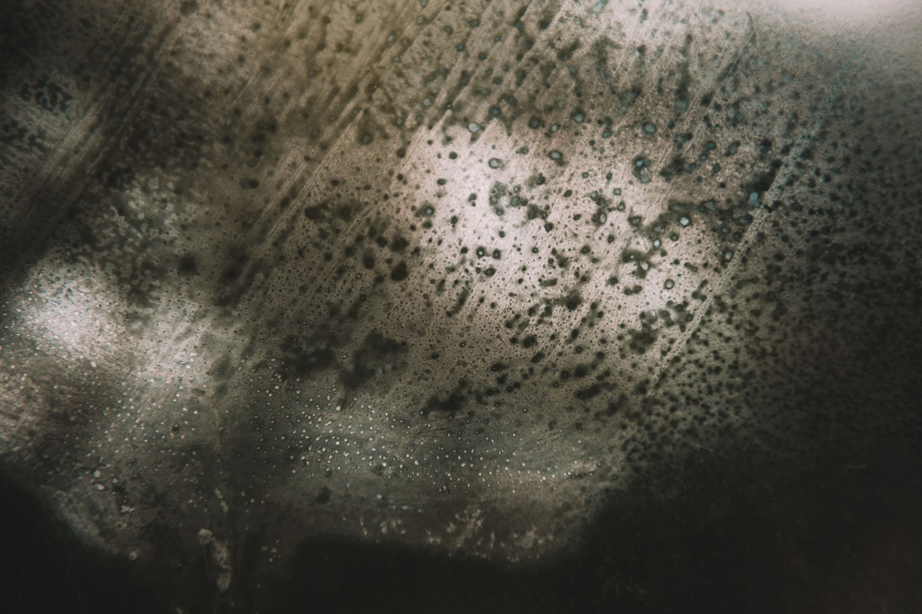 Mysterious abstract image featuring textured surface and light reflections creating a moody atmosphere.