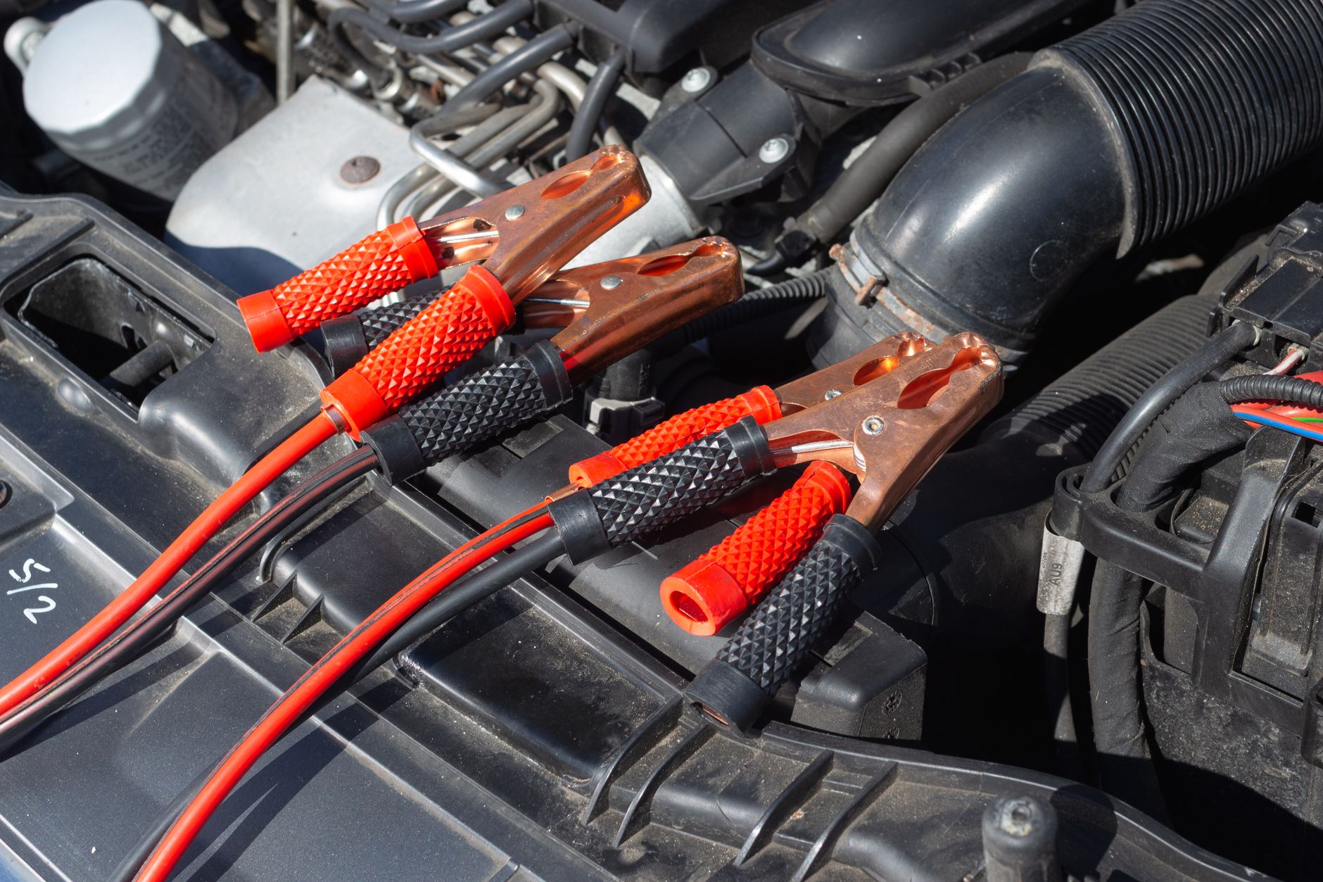 Close-up of car engine with attached jump starter cables