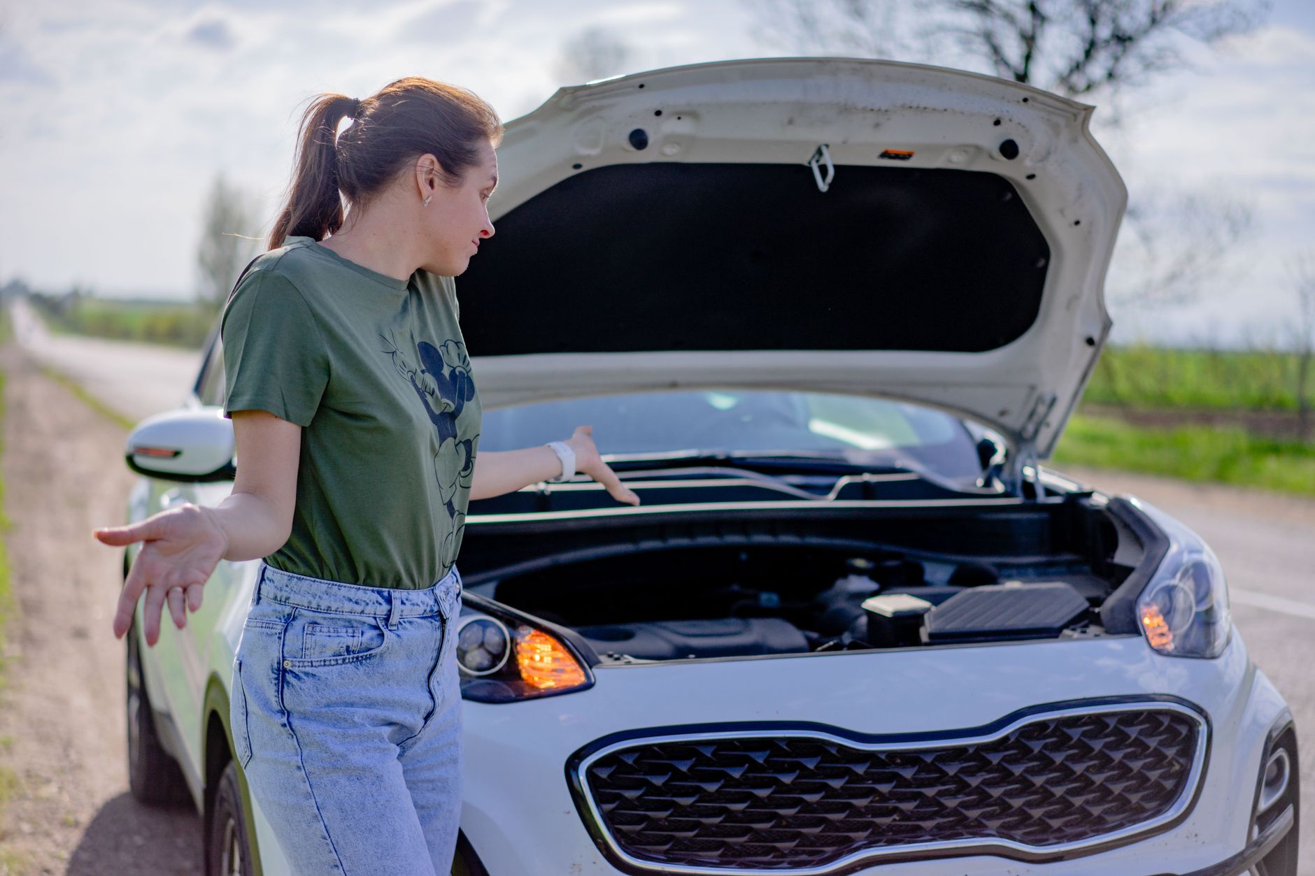 Woman waiting for roadside assistance by her broken down car