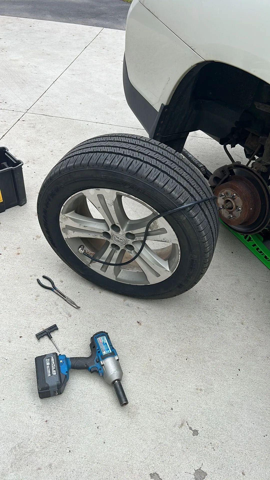 A tire is being changed on a car with a wrench.