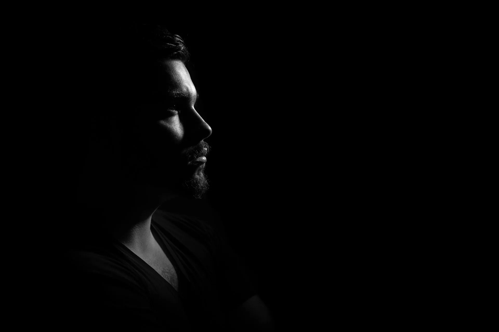 A black and white photo of a man's face in the dark