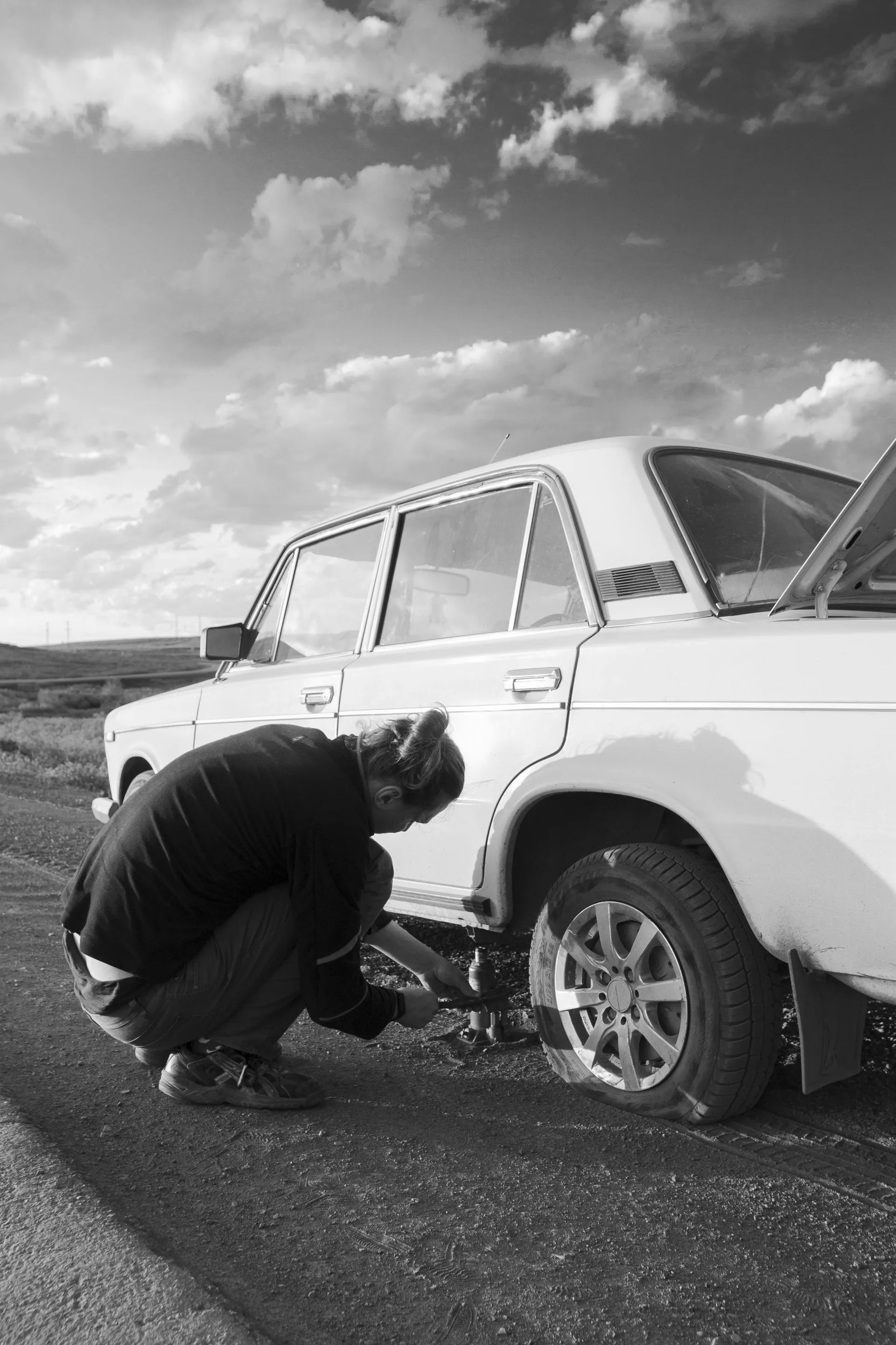 A man is changing a tire on a white car
