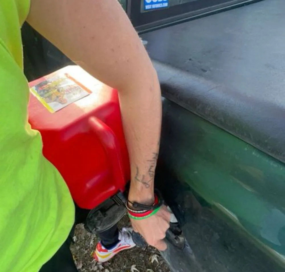 A woman is pumping gas into a green truck
