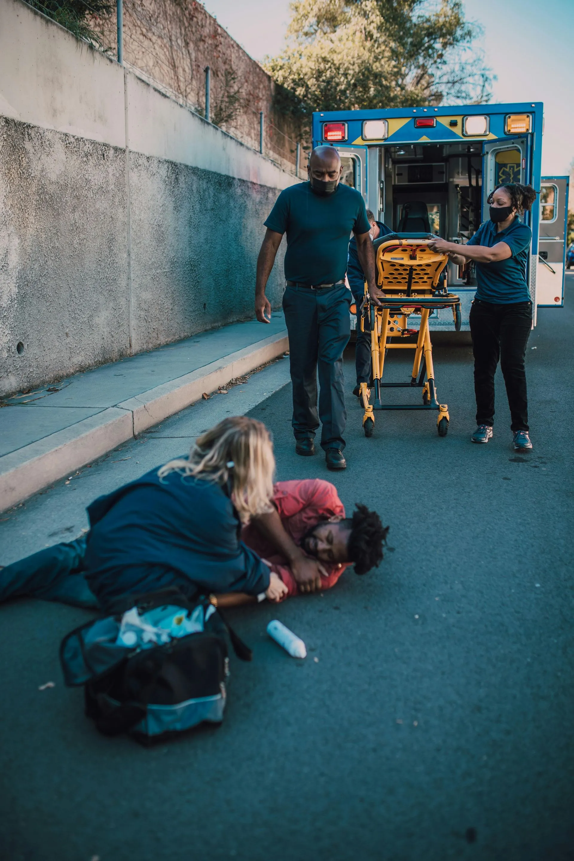 A man is laying on the ground with an ambulance in the background