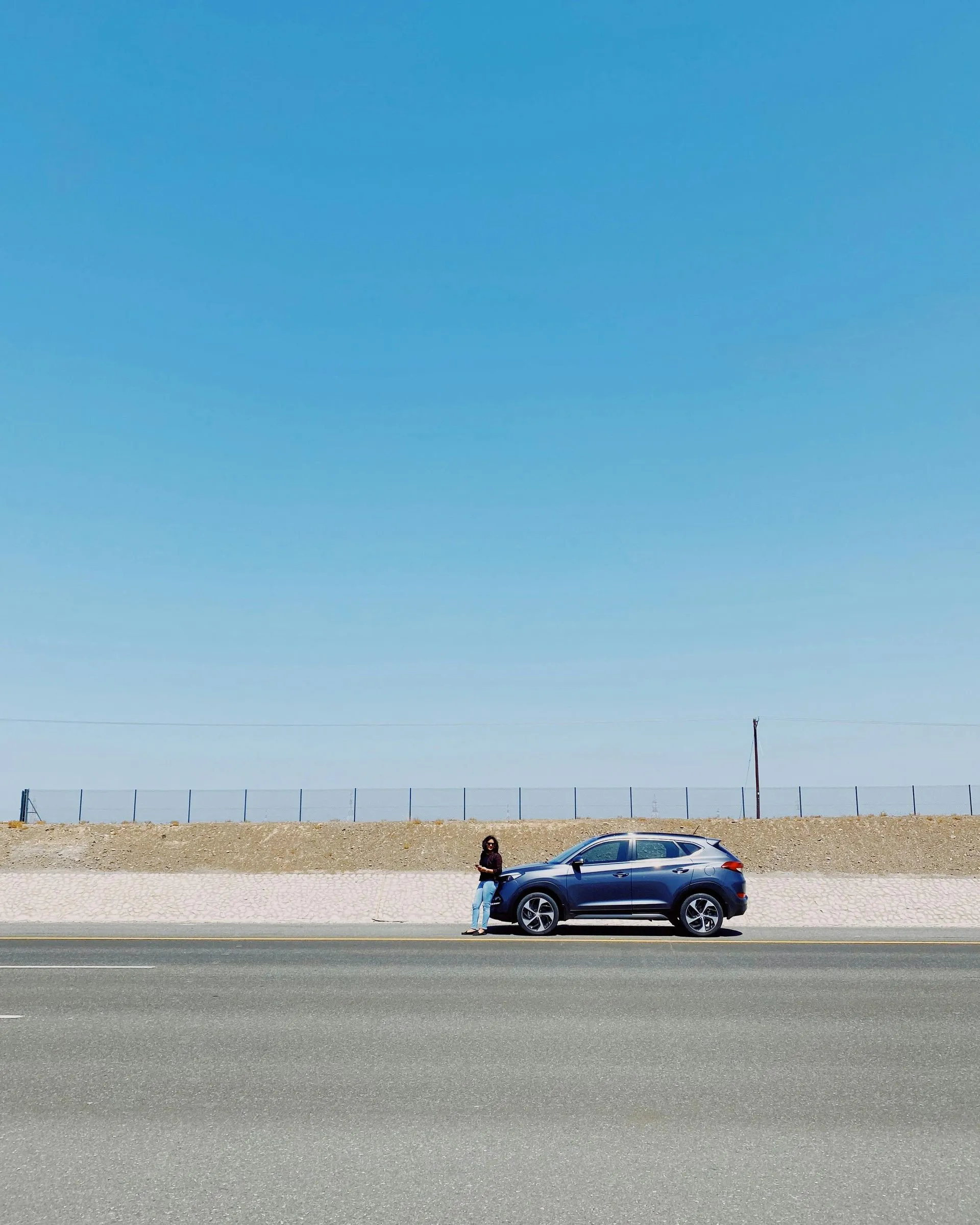 Blue car parked on the side of the road in the desert