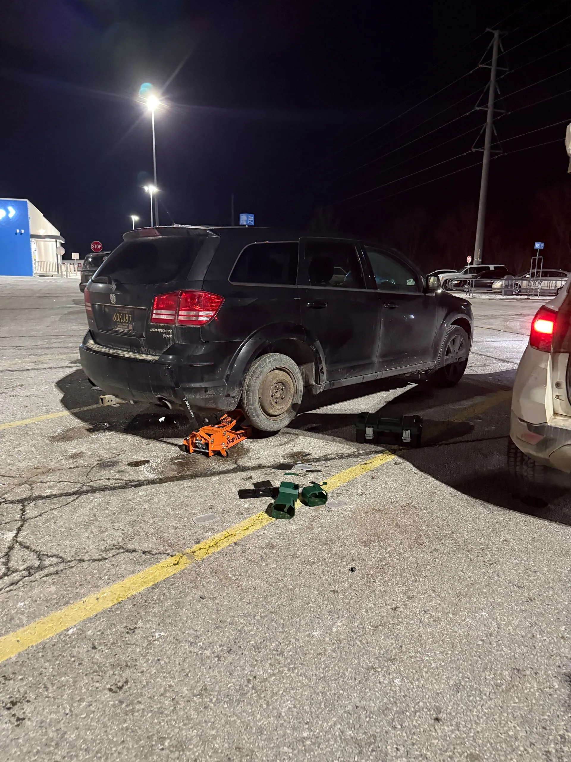 Car sitting on a jack in a parking lot at night