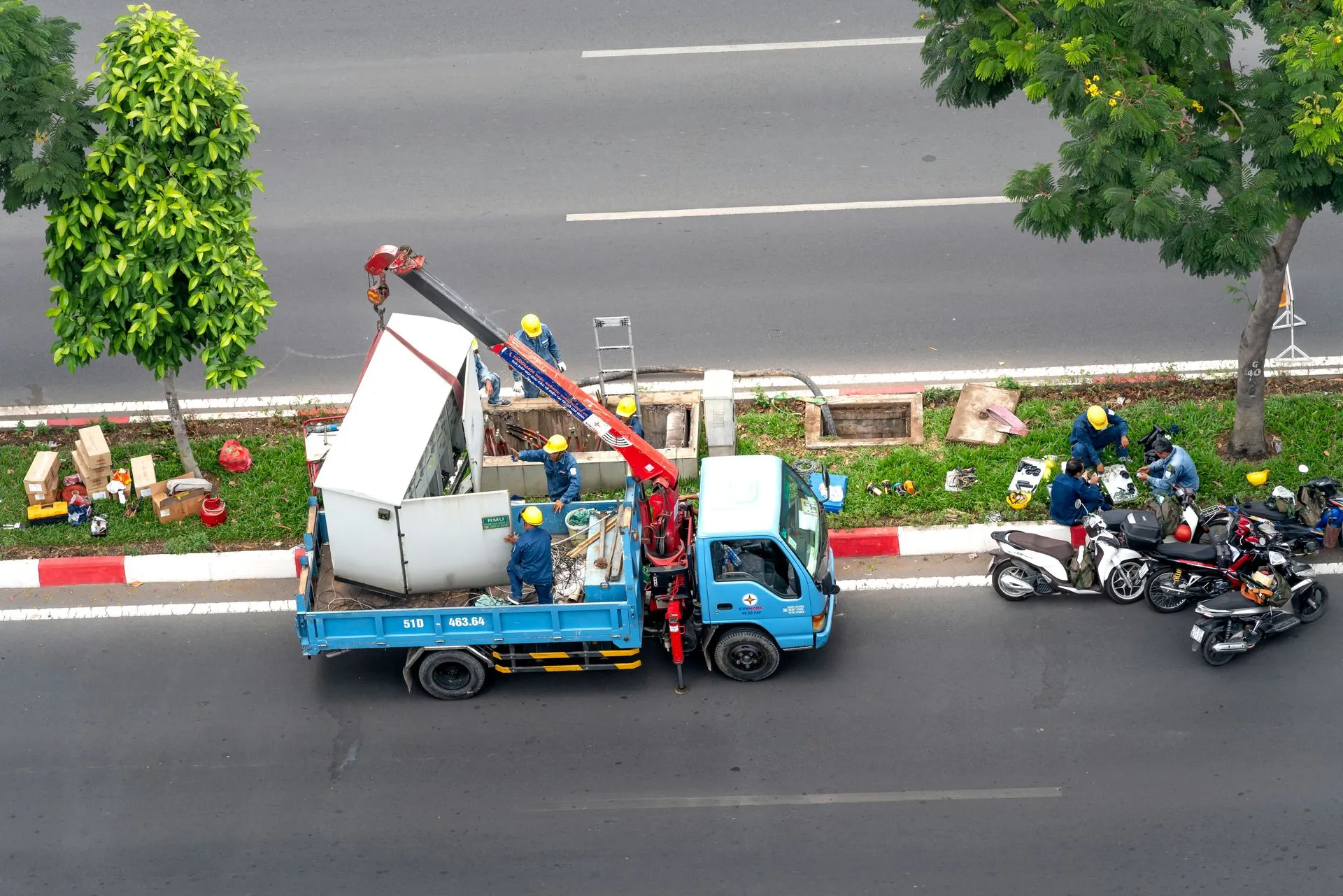 A blue truck with a crane on the back is parked on the side of the road