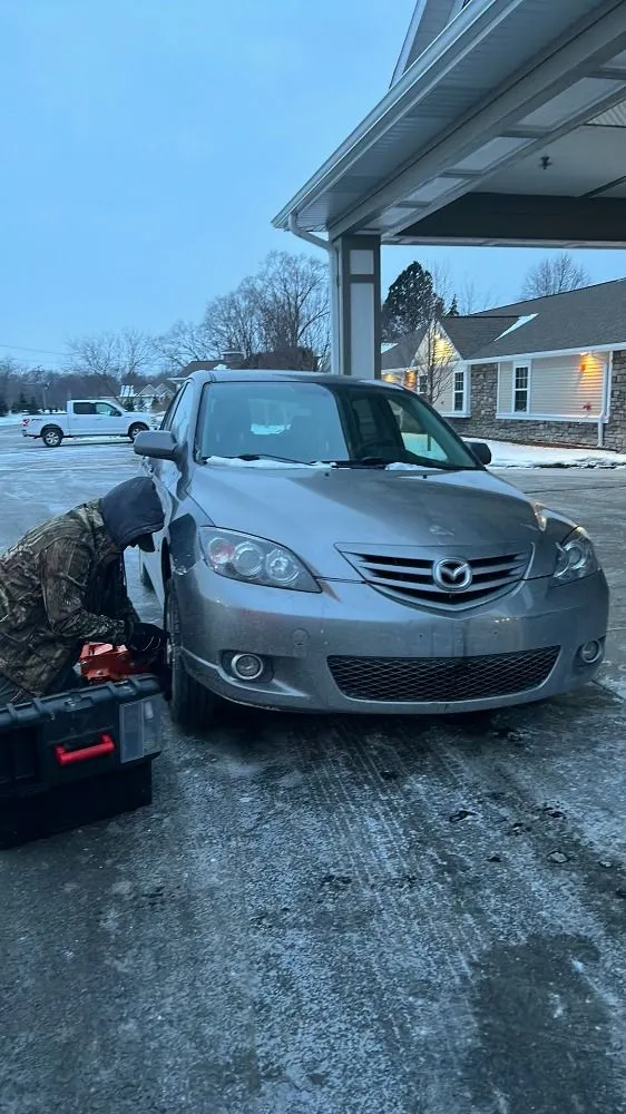 Man working on a car in the snow