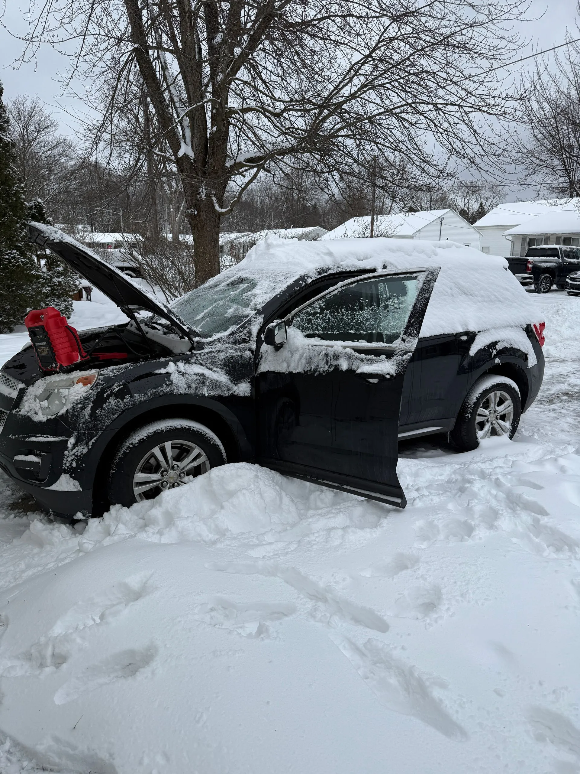 A car is stuck in the snow with its hood open.
