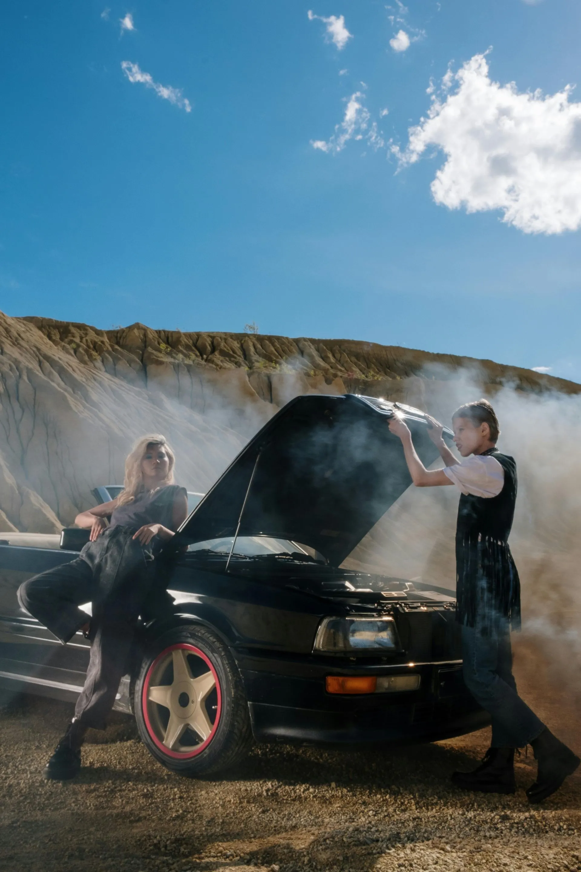 A man and a woman working on a broken down car