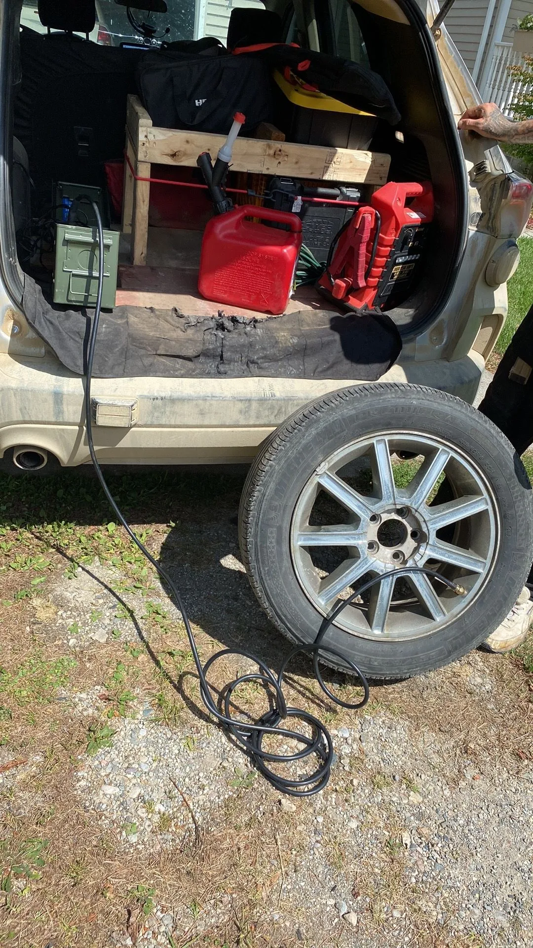 A person is plugging a tire into the back of a car.